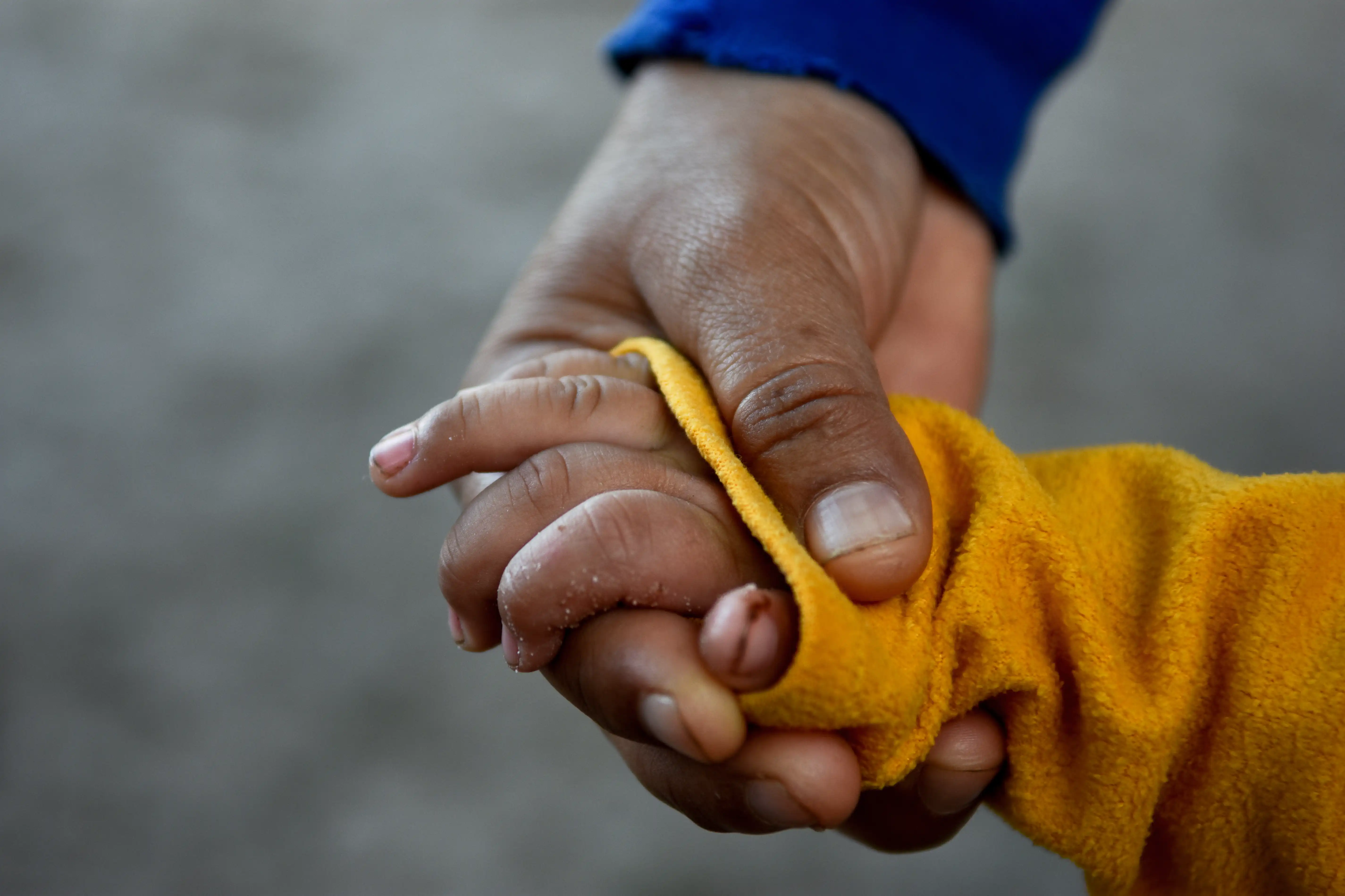 Mano de un adulto sosteniendo a la mano de un menor